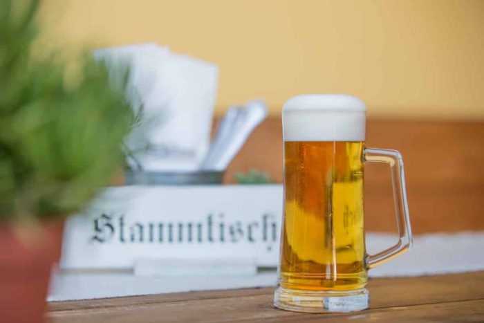 Frisches Bier im Krug auf Holztisch, Stammtisch-Schild, gemütliches Wirtshaus Hotel Kirchenwirt