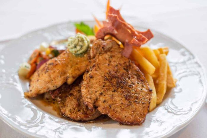 Herzhafte Fleischplatte mit Kräuterbutter, Pommes, Speck und buntem Gemüse im Hotel Kirchenwirt