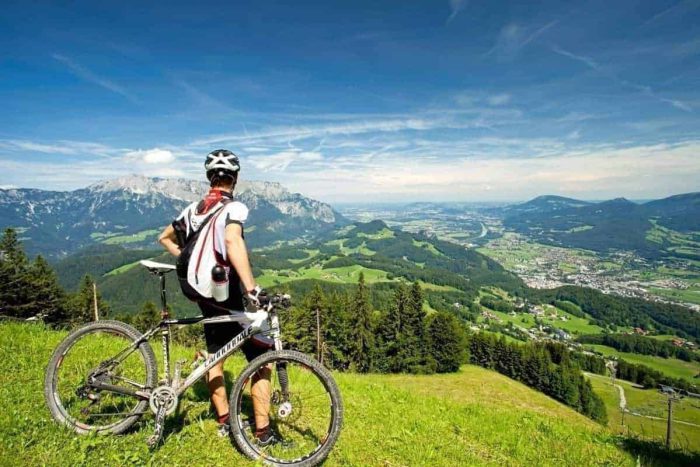 Radfahrer genießt Bergpanorama über dem grünen Salzburger Land bei Puch, Sommerurlaub Aktivhotel