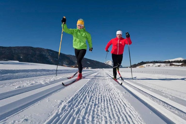 Zwei Langläufer auf perfekt gespurter Loipe vor Bergkulisse bei Puch, Winterurlaub Salzburg