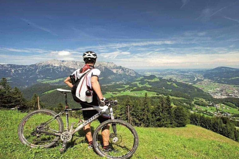 Radfahrer mit Mountainbike genießt Panorama über grüne Berge bei Puch, Salzburg, Tennengau